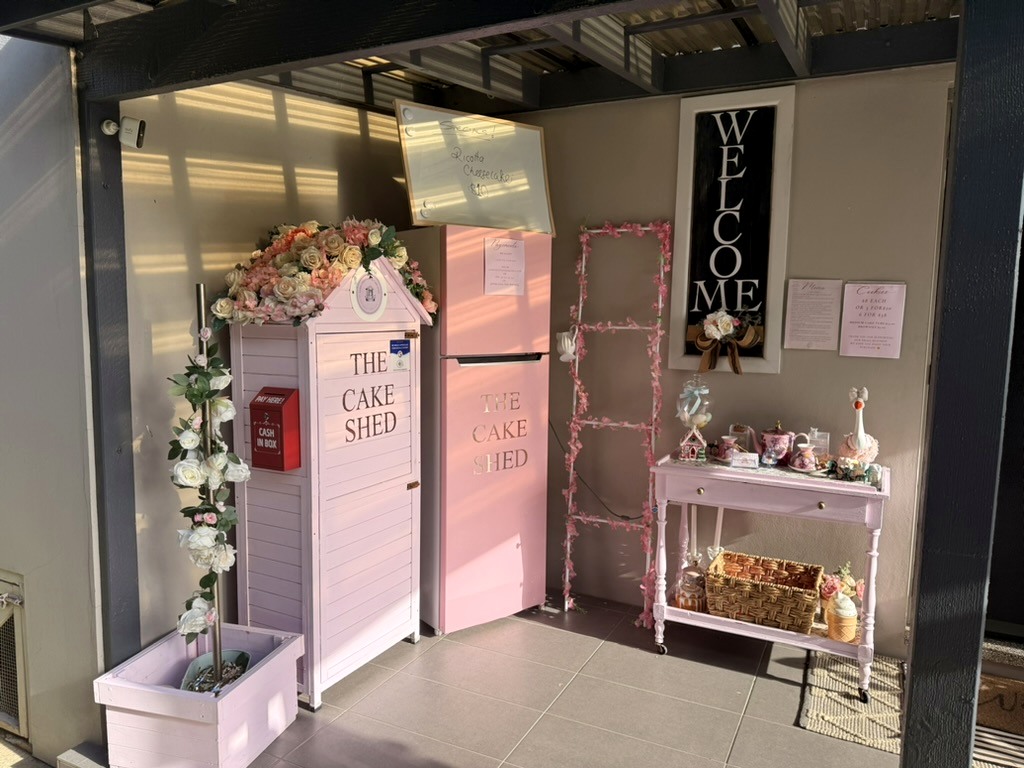 The real Cake Shed porch with pink floral display and Cake Shed refrigerator