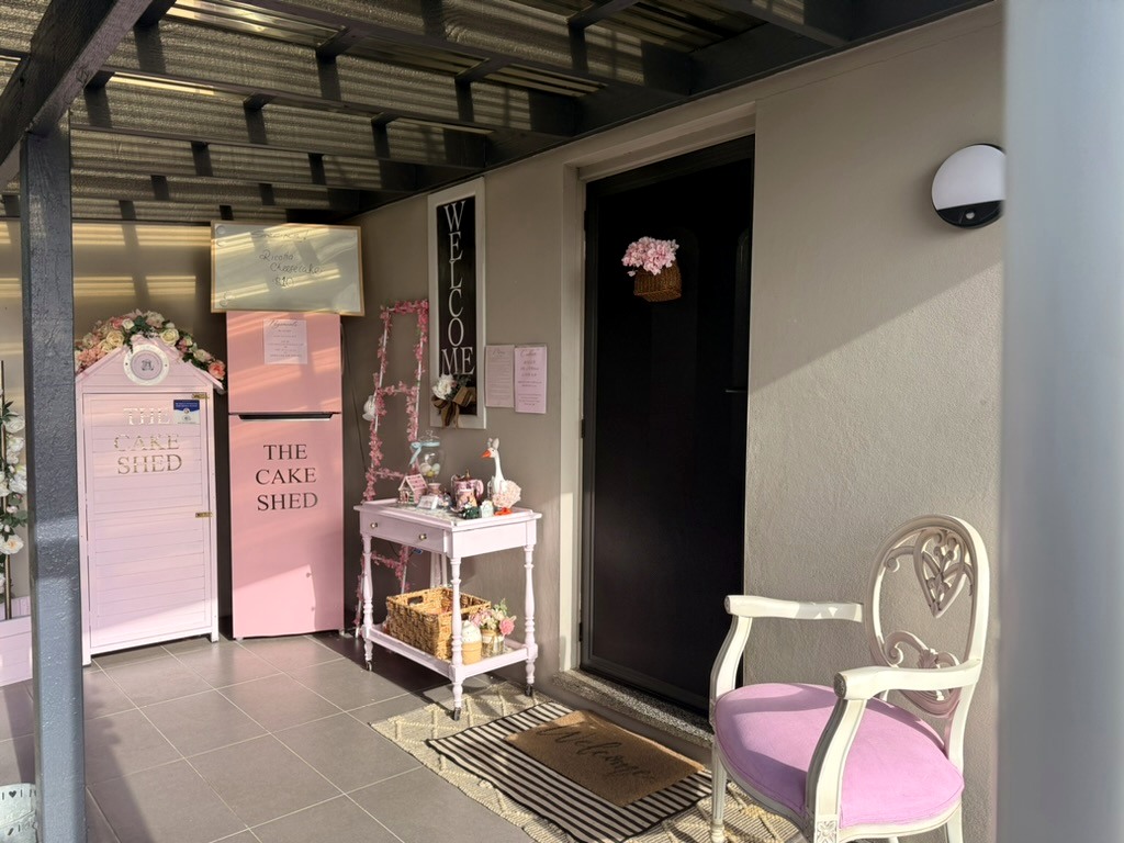 The real Cake Shed porch entrance with pink chair and welcome sign